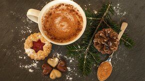 Weihnachtsplätzchen, Zimt, Kakao und Tannenzapfen auf hölzernem Untergrund